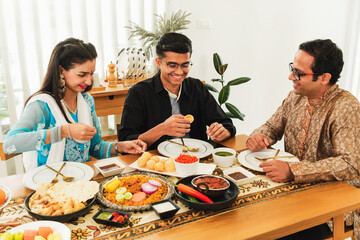 Happy Indian family enjoying traditional dinner together at home with authentic dishes like biryani...