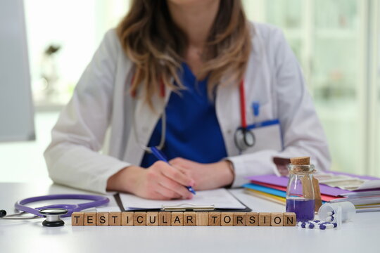 A healthcare professional in a clinical setting discusses and writes about the important topic of testicular torsion