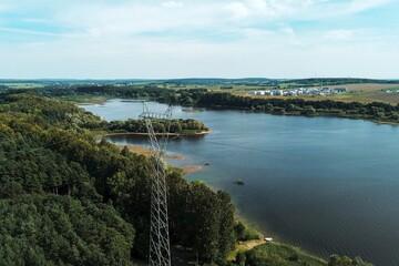 Electricity transmission tower by lake and forest