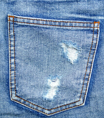Close-up of a distressed denim jacket pocket with fashionable ripped frays and raw edges. Trendy...