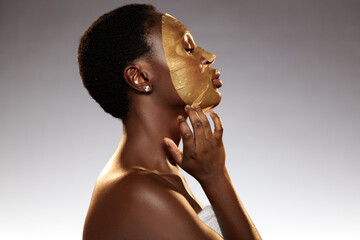 Woman applying gold facial mask in spa setting during a self-care ritual for rejuvenation and...