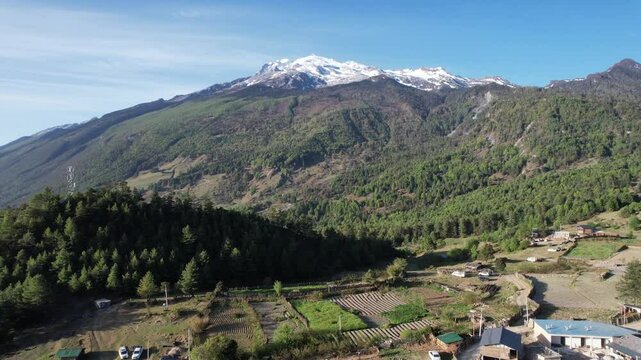 Drone view of Haba Village in the mountains with snowy peak on a sunny day with blue sky