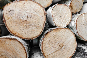 Stack of chopped birch logs prepared for firewood, showing natural textures and wooden surfaces in...