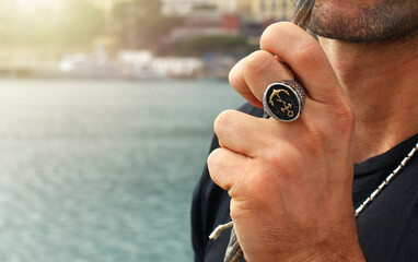 Fototapeta premium Sailor showing golden anchor ring while holding rope in port