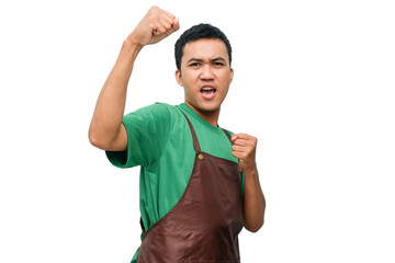 Young man in green shirt and brown apron making a victory celebration gesture with an enthusiastic...