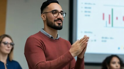 Young hispanic male presenting in an office with colleagues and graph in background - Powered by Adobe