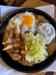 Frying pan with fried meat, potato pancakes, sour cream and cabbage, hearty rustic breakfast