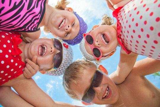 Little girls in bathing suits have fun during summer time on the lake beach.