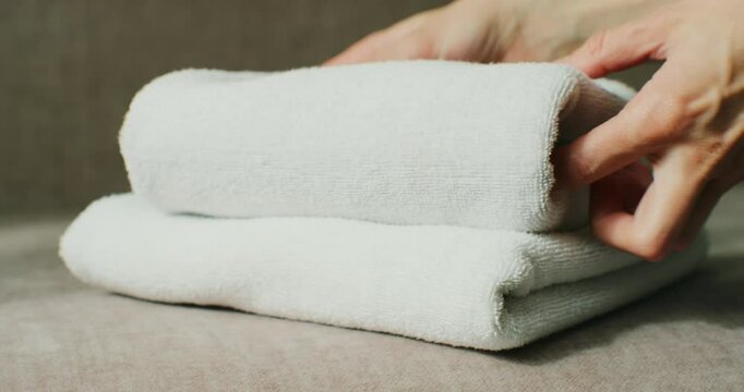 Young woman putting washed dry clean towels on iron board, preparing for ironing.