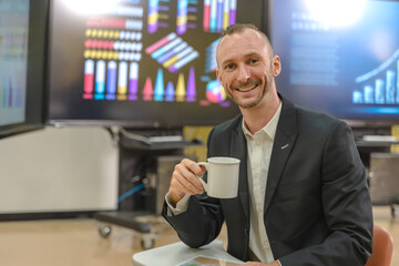 Male Caucasian businessman in suit drinking coffee working in conference meeting room