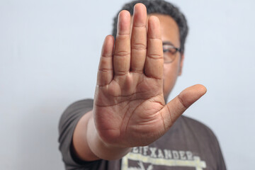 Male individual raises hand with palm facing forward showing strong stop gesture in refusal or...