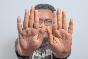 Man raises both hands forward with open palms in clear refusal or defensive stop gesture...
