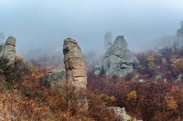 Rugged rock formations amid autumn foliage in Demerdzhi mountains, Crimea. Mist and overcast sky...