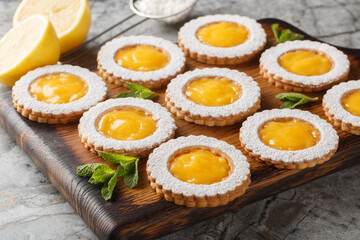 Lemon Curd Cookies feature a soft and buttery lemon cookie filled with a bright citrusy homemade lemon curd closeup on wooden board on the table. Horizontal