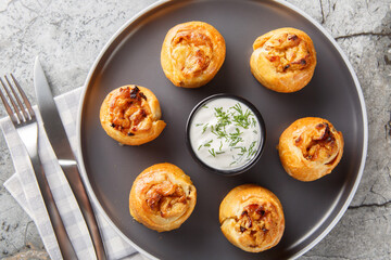 Knish is a delicious potato stuffed pies served with sour cream close-up in a plate on the table....