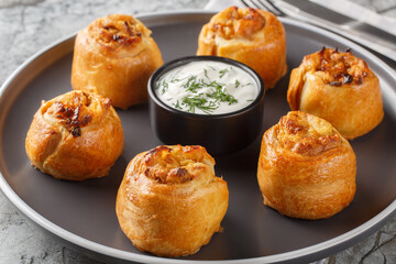 Knish is a delicious potato stuffed pies served with sour cream close-up in a plate on the table. Horizontal