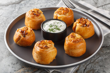 Ukrainian Knysh are pies with onion and potato filling served with sour cream close-up in a plate on the table. Horizontal