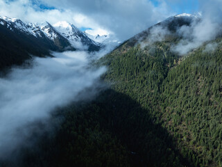Aerial view of beautiful high altitude snow capped mountain and forest landscape
