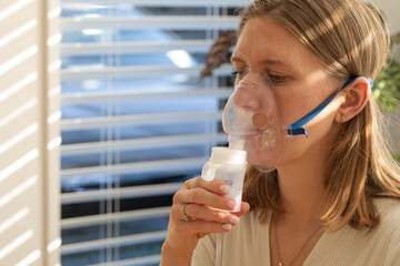 Female adult using nebulizer for respiratory treatment at home