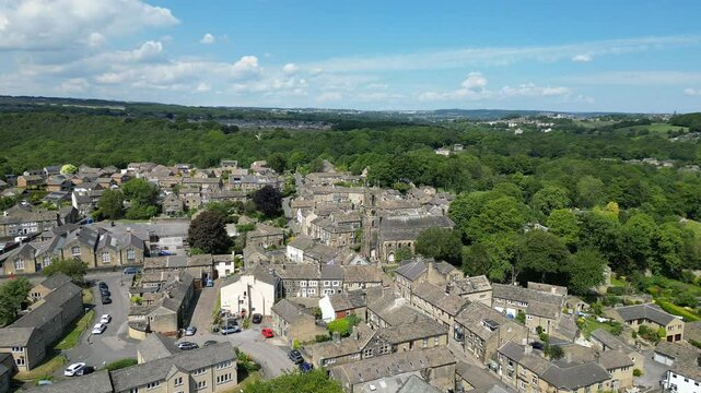 Drone view of the village of Honley Featuring St Mary's Church with lush greenery under clear sky