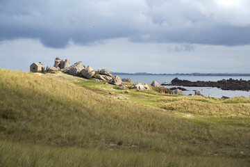 An old watch post stands on a grassy hill under a dramatic sky, showcasing the rugged beauty of Brittany. Plage des Amiets, France.