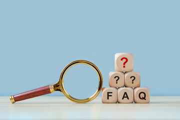 FAQ, frequently asked questions concept. FAQ wooden blocks isolated with Magnifying glass on blue...