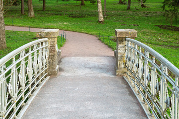 Close-up view of decorative iron bridge railings and stone pillars at park entrance, blending historical detail with natural surroundings.