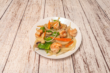 A plate full of stewed shrimp with crispy sauteed vegetables and spicy sauce