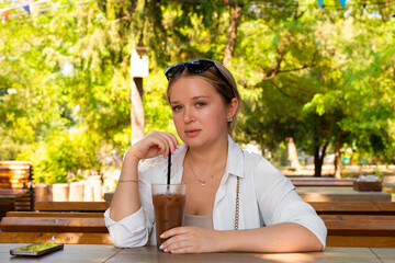 Pretty young girl wearing shorts and a white shirt in the summer park