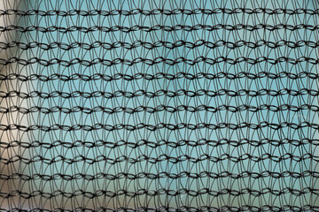 Black synthetic mesh on blue background close-up of thread pattern for backdrop, texture