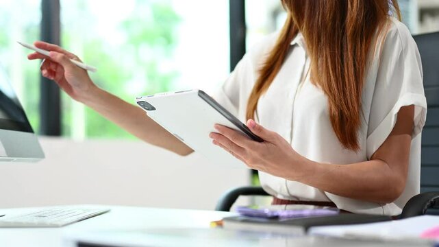 Hands of woman using tablet in modern office with laptop and digital tablet at office