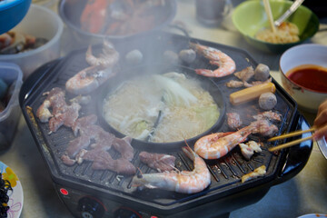 Cropped view of people eating meat and seafood on electric pan