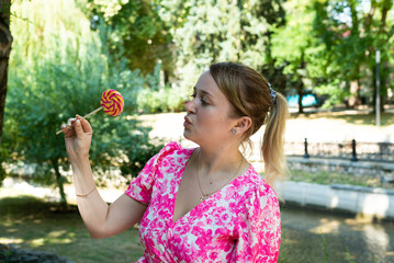 Pretty blonde girl wearing pink and white dress in the park