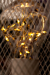 Garland inside a light bulb on a metal mesh background, warm light, decoration