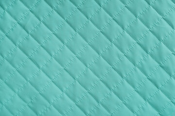 Obraz premium Checkered, diamond stitching pattern, turquoise quilted fabric background. Blanket or puffer jacket, stitch rhombus texture close up, macro. Wallpaper, backdrop.