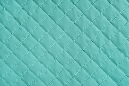 Checkered, diamond stitching pattern, turquoise quilted fabric background. Blanket or puffer jacket, stitch rhombus texture close up, macro. Wallpaper, backdrop.