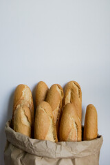 Fresh baguettes in brown paper bag against plain background