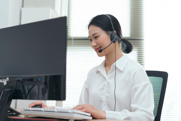 Young woman in headset working at computer in modern office environment during daytime