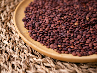 Organic uncooked seeds dark red brown lentils.