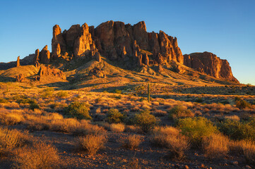 Sunset view of the Superstition Mountains with desert vegetation in Lost Dutchman State Park, Arizona.