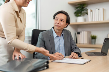 Professional Discussion and Document Review. Businessman signing paperwork during a meeting with a colleague.