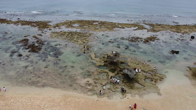 4K The serene seascape of Okinawa showcases crystal-clear waters, exposed rocky formations, and gentle waves lapping against the shore