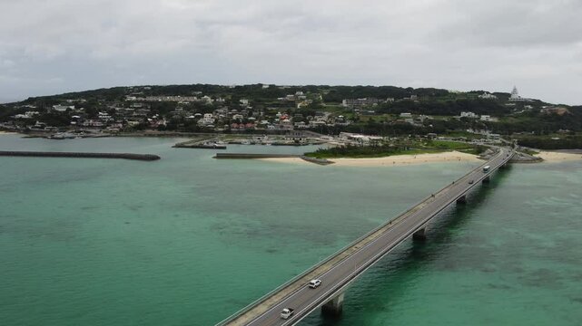 4K focus on road over Long bridge of Kouri Island and beach from a high view by drone with clear sky and sea water.