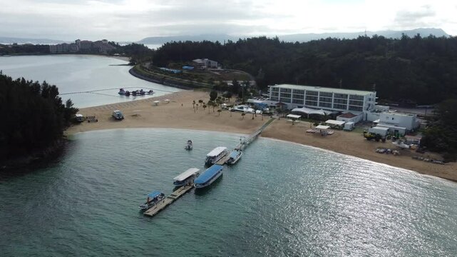 4K over the serene seascape of Okinawa showcases crystal-clear waters, exposed rocky formations, and gentle waves lapping against the shore