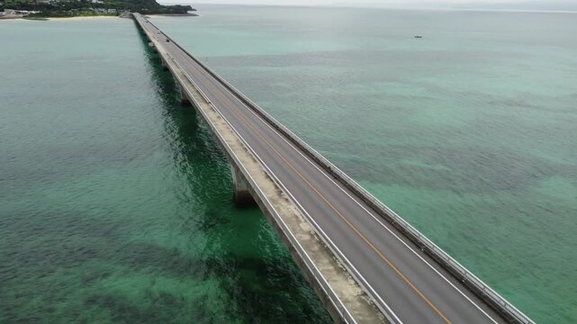 4K over the serene seascape of Okinawa showcases crystal-clear waters, exposed rocky formations, and gentle waves lapping against the shore