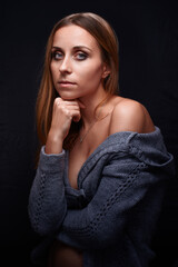 Portrait of a Thoughtful Woman in Cozy Sweater Against Dark Background..