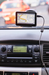 Fototapeta premium View of a car's dashboard featuring a GPS device displaying a route and an audio player interface labeled 'music.' Modern driving technology and convenience emphasized.