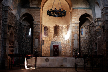 Beautiful stone church interior featuring an illuminated altar with ornate details and warm light. Ancient structure exudes a solemn atmosphere, showcasing its historical and spiritual significance.