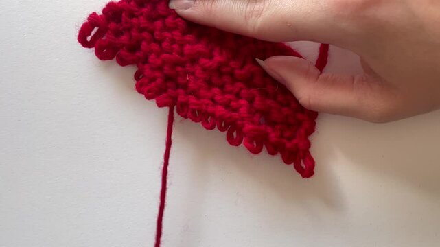 Going back on knitting stitches with thick red harn