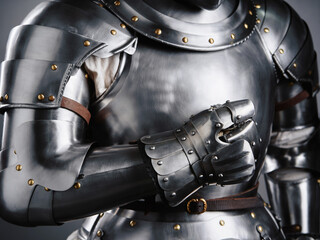 Close-up of a medieval suit of armor showing articulated gauntlet, polished steel plates, and brass...